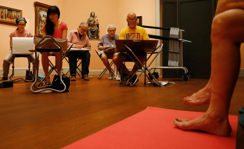 A live figure-drawing session held among artworks in a museum gallery, part of Adam Rozan's Nude Drawing in the Galleries program at the Worcester Art Museum.